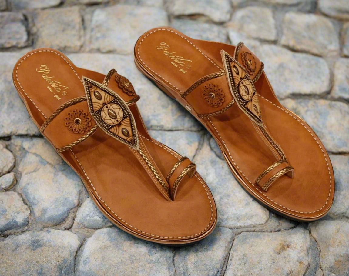 Pair of brown sandals with decorative straps on a white background