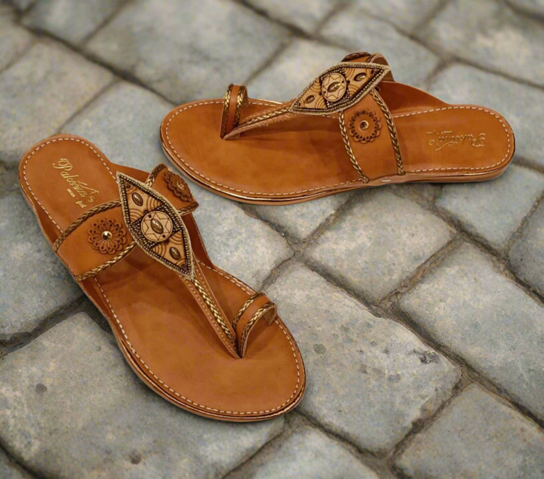 Pair of brown leather sandals with intricate designs on a white background
