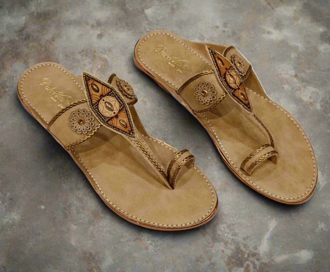 Pair of tan sandals with decorative straps on a white background