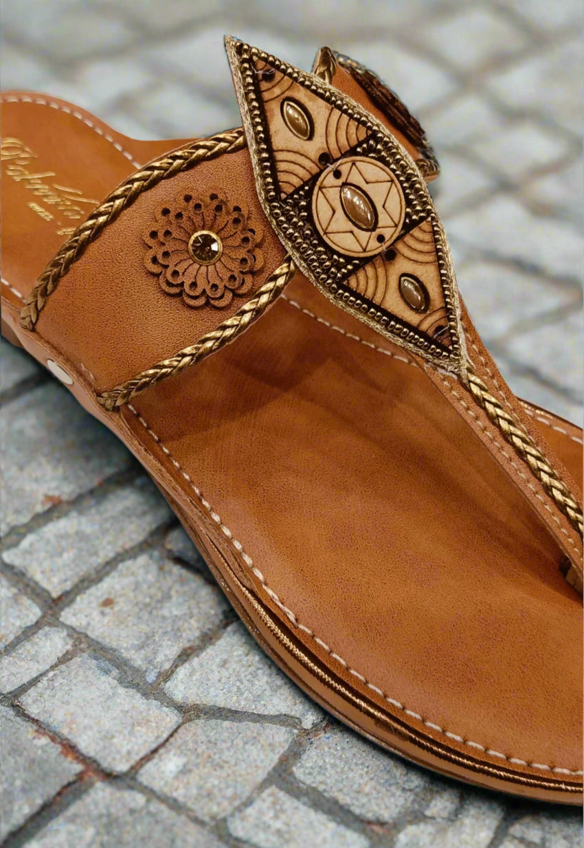 Brown sandal with intricate gold designs on a white background